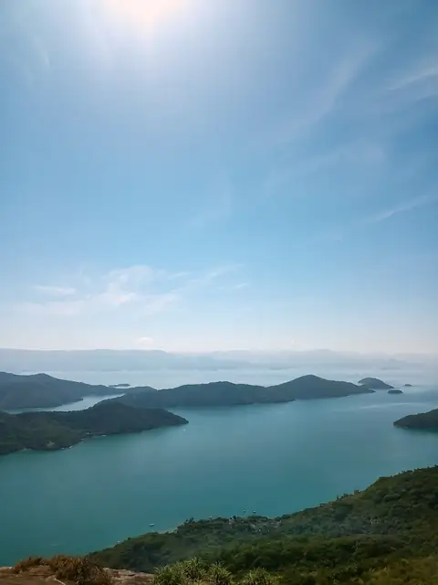 Vista do alto de uma baía de águas turquesa com ilhas e montanhas ao longe